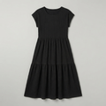 A black short-sleeve tiered dress with a textured, ribbed fabric, shown flat against a light gray background.