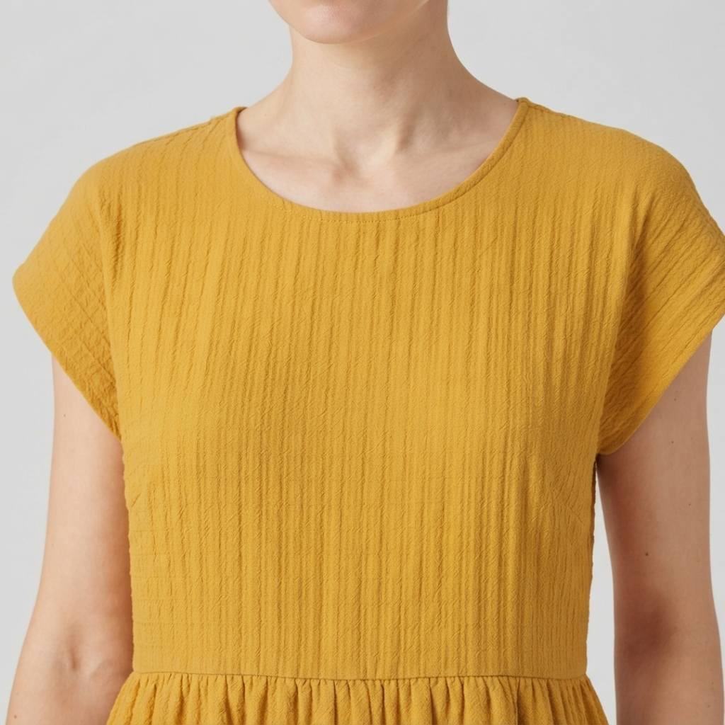 Close-up of a woman wearing a light beige short-sleeve blouse with gathered puff sleeves and a round neckline.