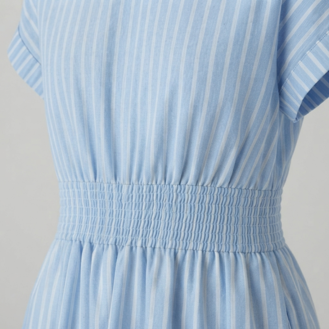 Close-up of a light blue and white vertically striped dress with a smocked waistband and short sleeves.