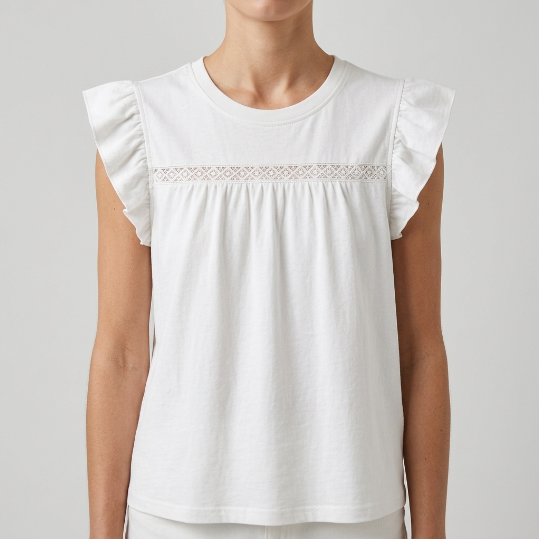 A woman wearing a white sleeveless top with ruffled cap sleeves and a delicate lace band across the chest, shown against a plain light gray studio background.