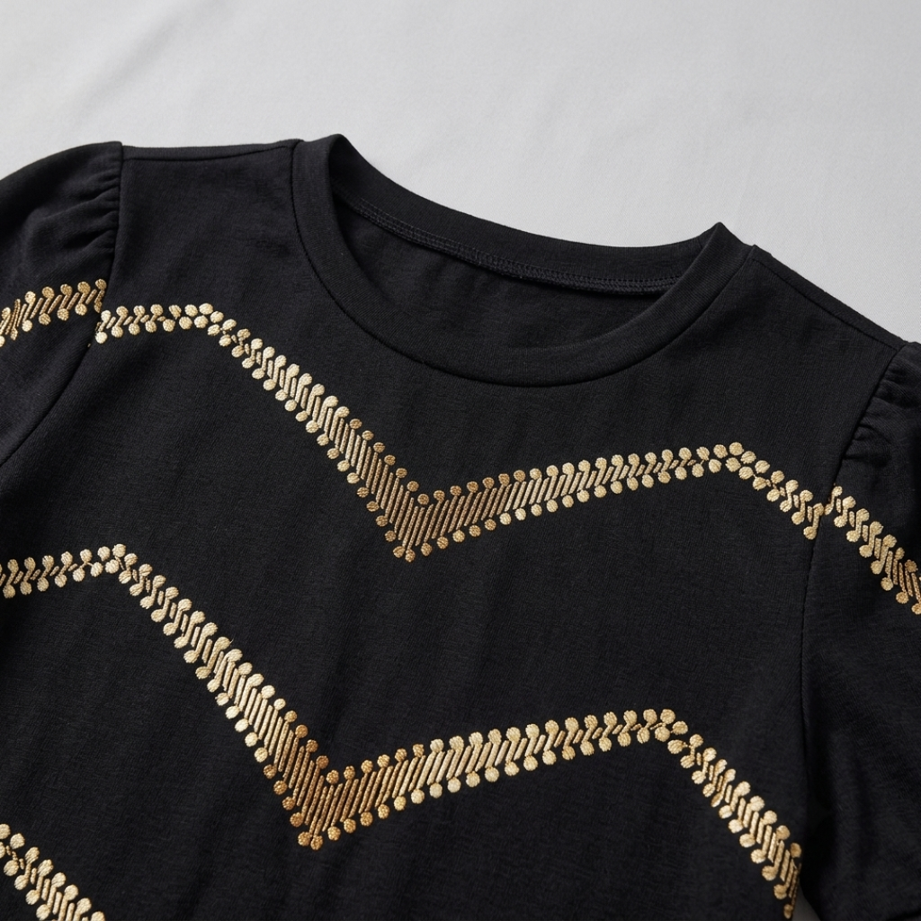 A close-up of a black long-sleeve top with gold chevron-patterned sequin embellishments, featuring puffed shoulders and a crew neck.