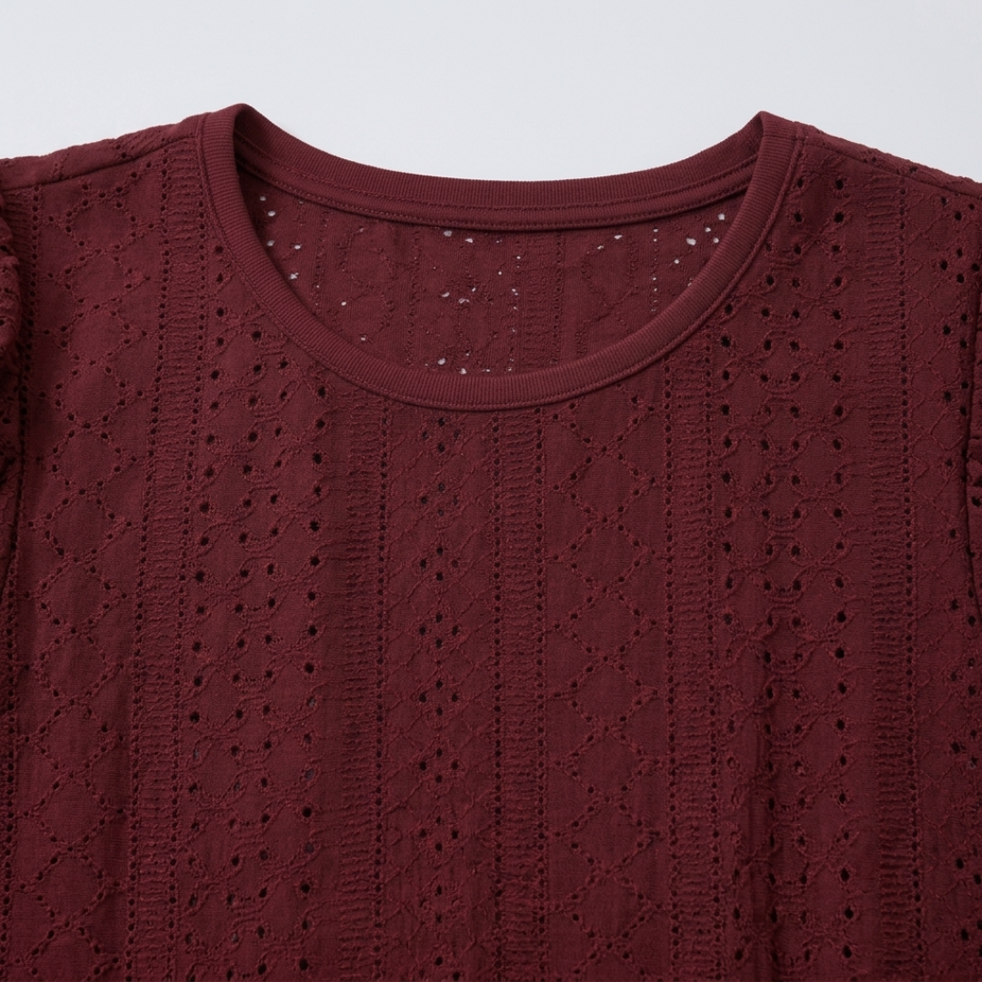 Close-up of a burgundy eyelet knit top showing the detailed textured fabric and crew neckline.