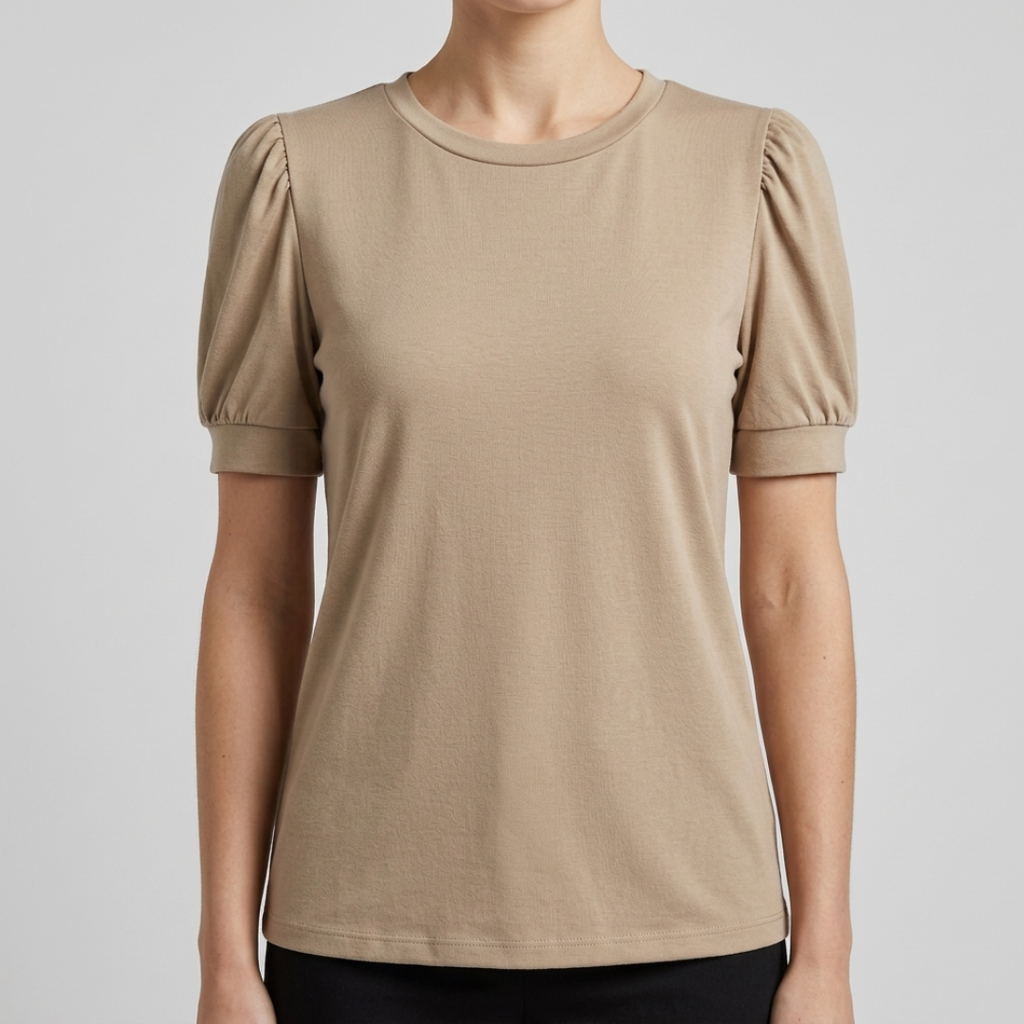 A woman wearing a beige short-sleeve crewneck top with puffed sleeves, shown from the neck down against a light gray studio background.