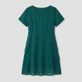 A short-sleeve, crew-neck dress in a rich emerald green color, featuring a tiered ruffle design on the skirt, shown against a neutral light gray background.